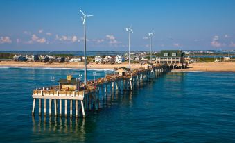 a long pier with multiple wind turbines , surrounded by a body of water and a town in the background at Holiday Inn Express Nags Head Oceanfront