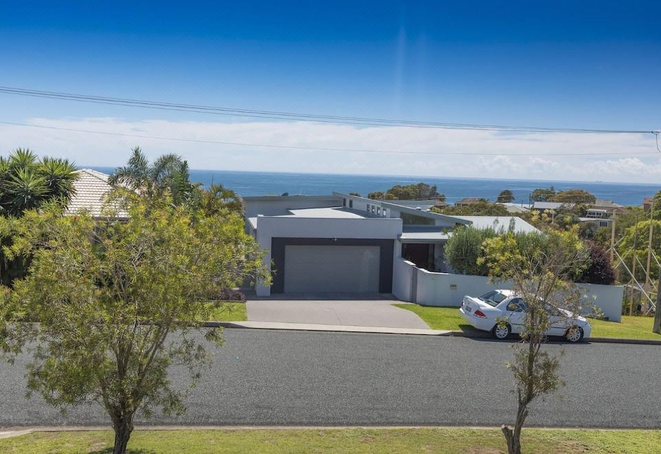 a large house with a garage and a driveway , surrounded by trees and overlooking the ocean at Hamptons