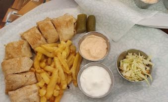 a table with plates of food , including french fries and pickles , accompanied by dipping sauces at Green Hill Hotel
