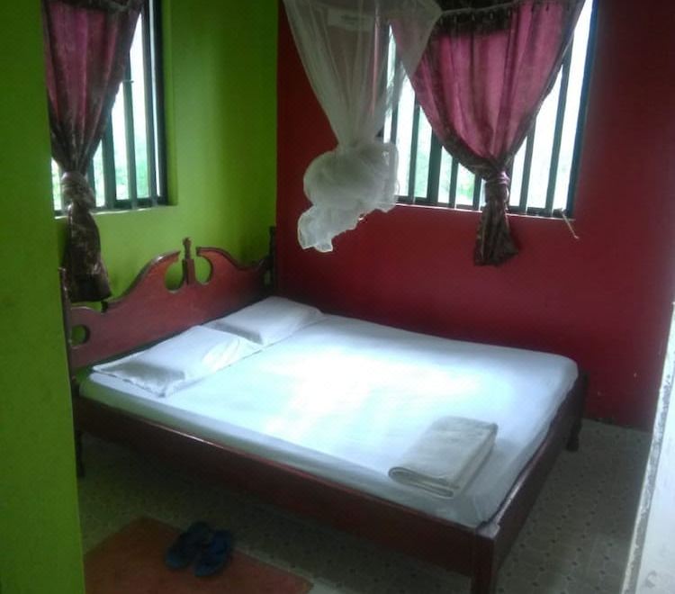 a bed with white sheets and a canopy is in a room with green walls at Eddys Resort