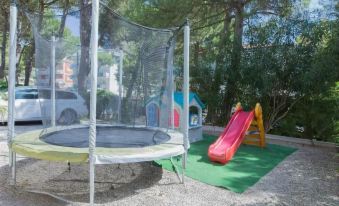 a backyard with a trampoline , slide , and play area for children , surrounded by trees and a wooden fence at Hotel New York