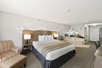 a large bed with white linens and a striped blanket is in the middle of a room at Country Inn & Suites by Radisson, Watertown, SD