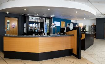 a modern bar with wooden and black counter , multiple dispensers , and an overhead light , set against a blue wall at Holiday Inn Express Newcastle Gateshead