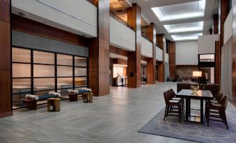 a large , modern hotel lobby with multiple floors and high ceilings , featuring a dining area with chairs and tables at Winston-Salem Marriott