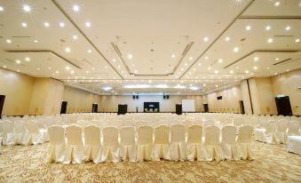 a large conference room with rows of white chairs and a stage at the front at Permai Hotel Kuala Terengganu