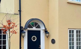 a house with a black door and an arched window , surrounded by a brick wall at Riverside Inn