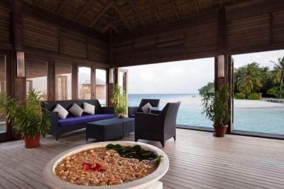 a wooden deck overlooking the ocean , with a fire pit in the center of the area at Vilamendhoo Island Resort & Spa