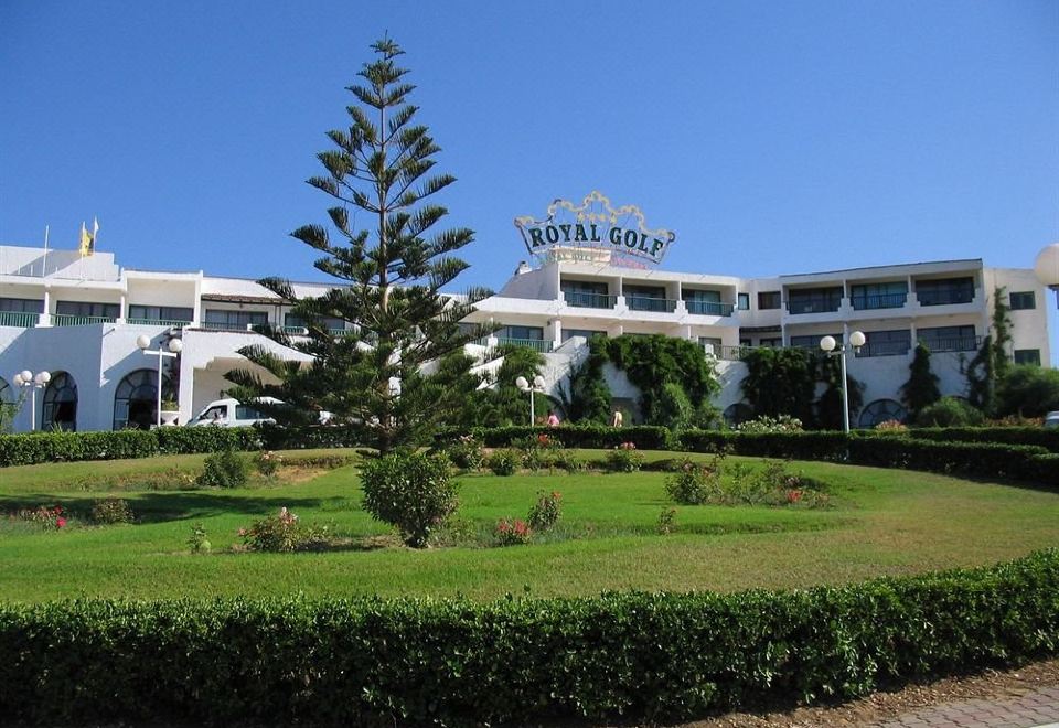 "a large building with a sign that reads "" royal golf "" is surrounded by green grass and trees" at Royal Golf