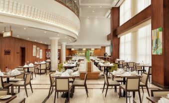 a large , modern dining room with multiple tables and chairs arranged for a group of people to enjoy a meal together at Hilton Garden Inn Al Jubail