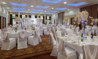 a large banquet hall with white tablecloths and chairs set up for a formal event at DoubleTree by Hilton Glasgow Westerwood Spa & Golf Resort