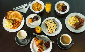 a table is set with a variety of breakfast foods , including pastries , fruits , and beverages at Holiday Inn Express Stevenage