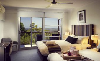 a modern hotel room with two beds , a balcony offering a view of the city , and various amenities at Mercure Clear Mountain Lodge