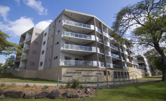 a modern apartment building with multiple balconies and a grassy area in front of it at Jacana Apartments