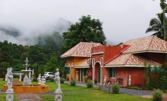 a traditional red and green house surrounded by a lush garden , with a statue in the foreground at Cinque Terre Resort