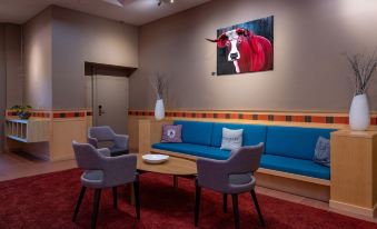 a living room with a blue couch , two chairs , and a painting of a bull on the wall at Arenas Resort Victoria-Lauberhorn