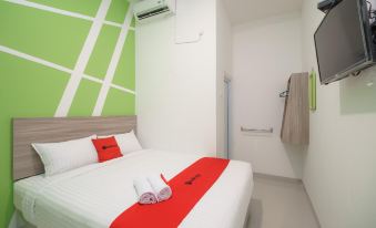 a clean and well - organized bedroom with a white bed , red sheets , and green walls at RedDoorz Plus Near Uin Raden Fatah Palembang