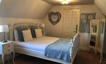 a white bedroom with a bed , a mirror , and a chandelier hanging from the ceiling at Deeping Stage