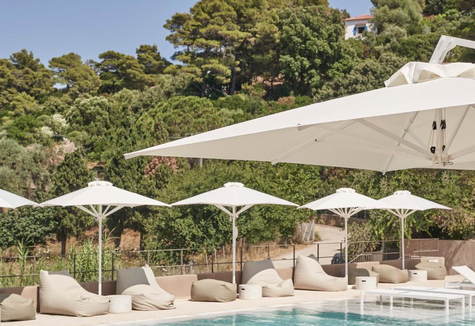 a luxurious hotel with a large outdoor pool surrounded by lounge chairs and umbrellas , providing a relaxing atmosphere at Radisson Resort Skiathos