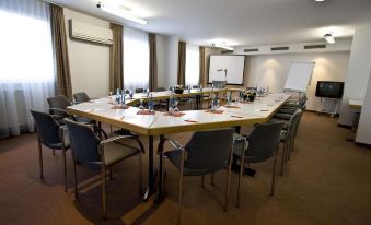 a conference room with a long table and chairs arranged in a semicircle , providing seating for a group of people at Highway Hotel