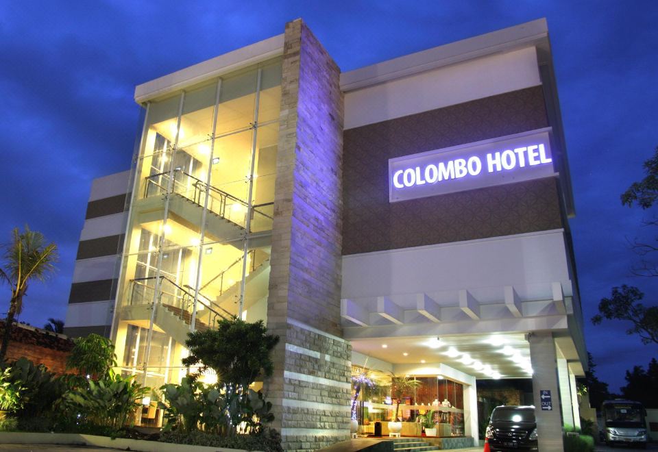 "a large building with a sign that says "" colombo hotel "" is lit up at night" at Bueno Colombo Hotel Yogyakarta