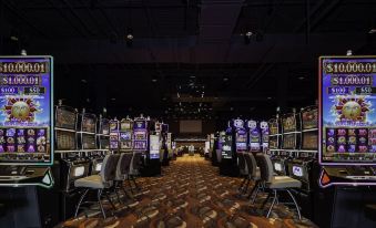 a large , empty casino room with rows of slot machines and a black ceiling , all under bright lights at Cahuilla Casino Hotel