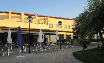 a yellow building with a large patio area containing several tables and chairs under umbrellas at Hotel Sierra Luz