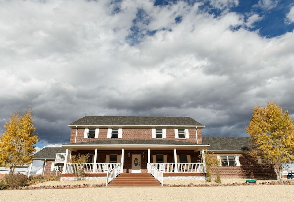 a large brown house with white trim and a balcony , set against a cloudy sky at Lamp Post Lodge