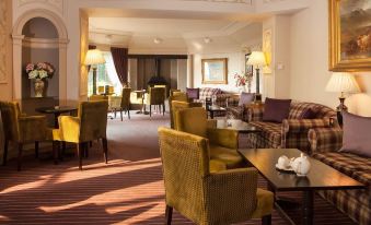 a spacious , well - lit living room with multiple chairs and couches arranged in a comfortable seating area at Old Manor Hotel