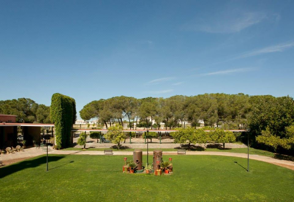 a grassy field with trees and bushes , as well as two columns of flowers in the foreground at Lantana Garden