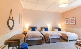 a room with three beds , each made up with white sheets and blue pillows , positioned next to each other at The Greenhead Hotel