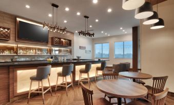 a modern bar with wooden floors , gray stools , and a large screen tv , surrounded by comfortable seating arrangements at Fairfield Inn & Suites Houston League City