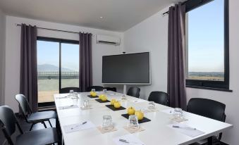 a conference room with a large screen , table set for a meeting , and black chairs at Hampton by Hilton Rome North Fiano Romano