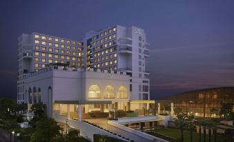 a modern hotel building with multiple stories and balconies , surrounded by trees and a path leading to it at Hyatt Centric Janakpuri New Delhi
