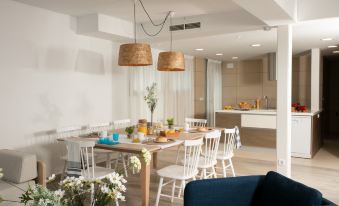 a dining room with a wooden dining table surrounded by white chairs , a blue couch , and a kitchen in the background at Pierre & Vacances Blanes Playa