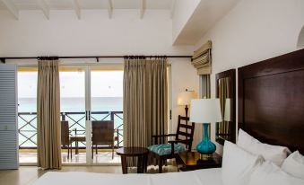 a hotel room with a large bed , a chair , and a view of the ocean at Infinity on the Beach