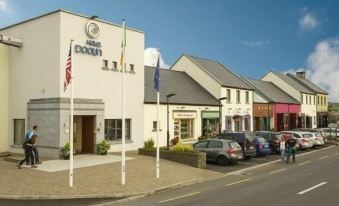 a row of buildings with flags and flags on poles in front of a street at Hotel Doolin