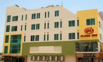 a large building with a green and white facade is next to an air conditioner at Plaza INN Hotel