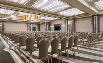 a large conference room with rows of chairs arranged in a semicircle , ready for an event at Ramada by Wyndham Ramnicu Valcea