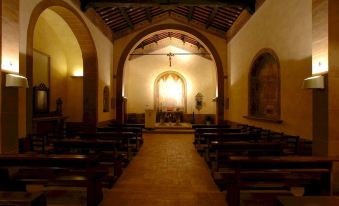 a church interior with rows of wooden pews and a large stained glass window at the altar at Abbadia Sicille Relais