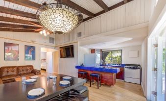 a modern kitchen and dining area with wooden floors , white walls , and a large chandelier hanging from the ceiling at Lime Tree Bay Resort