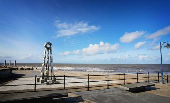 a view of the ocean from a pier , with a cloudy sky in the background at The Beaches Hotel