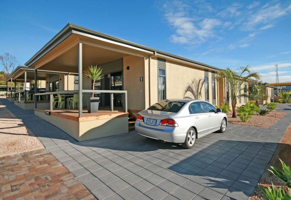 a white car is parked in front of a house with palm trees and other plants at Streaky Bay Hotel Motel