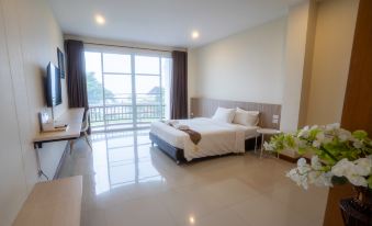 a modern bedroom with a large window and sliding glass door , featuring a bed , chairs , and potted plants at Vieng Khong Hotel