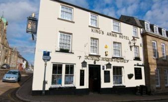 "a white building with a sign that reads "" kings arms hotel "" is shown on a street" at King's Arms