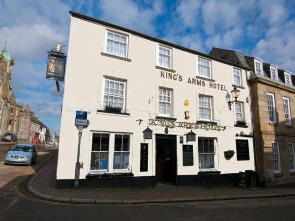 "a white building with a sign that reads "" kings arms hotel "" is shown on a street" at King's Arms
