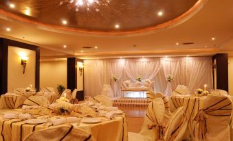 a large , elegant banquet hall with tables covered in white tablecloths and chairs arranged around them at Aracan Pyramids Hotel