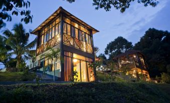 a modern wooden house with a balcony and large windows is lit up at night at Bilut Hills @ Bentong