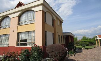 a large house with a red and white exterior , situated in a park - like setting with greenery at La Flor de la Canela