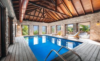 an indoor swimming pool surrounded by a wooden deck , with several people enjoying their time in the pool area at Aristi Mountain Resort