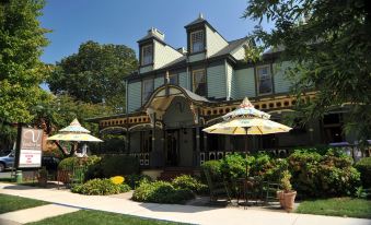 a large house with a green roof and yellow umbrellas on the front porch , surrounded by lush greenery at Vandiver Inn